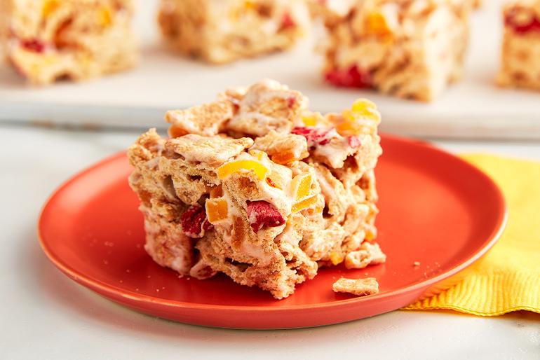 A No-Bake Fruity Cinnamon Toast Crunch™ Cereal Bar on a plate with the rest of the bars behind it.