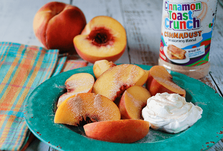 A bowl of Cinnadust™ Peaches and Cream with Cinnadust™ on the peaches and a jar of it behind.