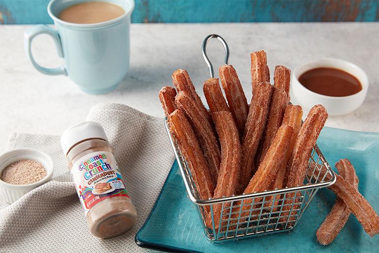 Cinnadust™ Churros in a metal basket with a jar of Cinnadust™ beside it.