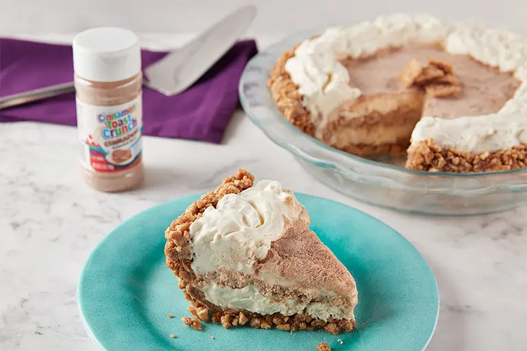 A slice of Cinnamon Toast Crunch™ Ice Cream Pie on a plate with more of the pie behind it.