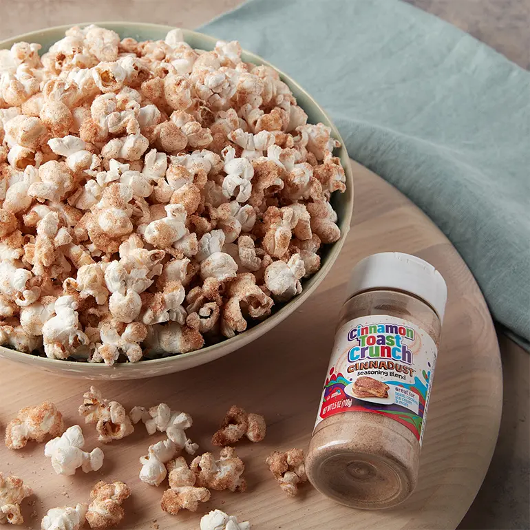 A bowl of Cinnadust™ Popcorn next to a jar of Cinnadust™.