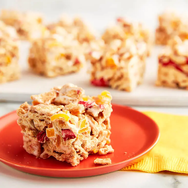 A No-Bake Fruity Cinnamon Toast Crunch™ Cereal Bar on a plate with the rest of the bars behind it.